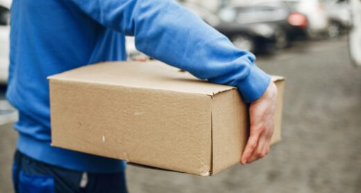 Une personne en tenue bleue transportant un colis dans la rue