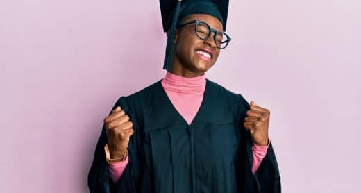 Jeune étudiante portant une toge et un chapeau de diplôme les bras en l'air